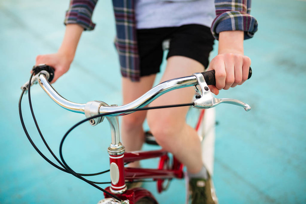 Lähikuva kuva nuoren miehen kehon ratsastus punainen polkupyörä puistossa. Kuva punainen klassinen polkupyörän koripallokenttä
 - Valokuva, kuva