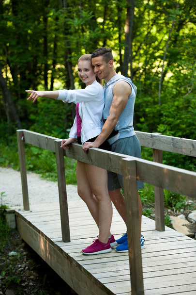 YActive young couple on a path in park, woman pointing at someth - 写真・画像