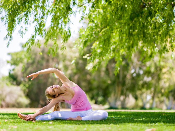 Young woman doing yoga in the park - Fotó, kép