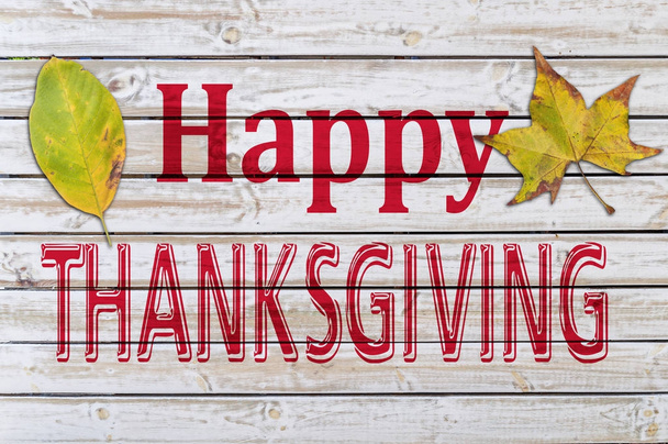 Joyeux Thanksgiving écrit sur une table en bois blanc avec deux feuilles d'automne
 - Photo, image