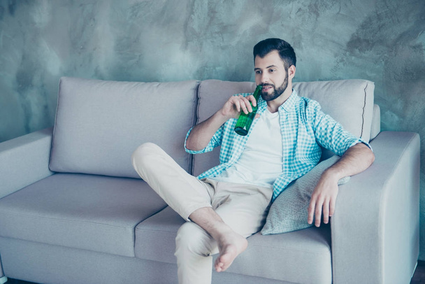 Young handsome man with bristle drinking beer, putting one leg o - Fotografie, Obrázek