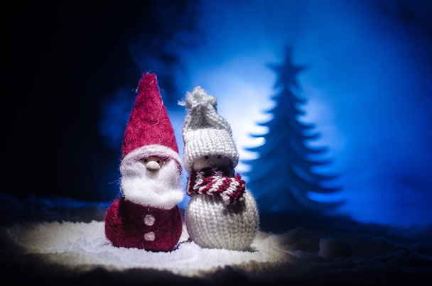 Joyeux Père Noël poupée sur le temps de Noël avec arbre et neige. Fond bokeh coloré. Santa Clause et Joyeux Noël modèle figurine jouet sur ton foncé
 - Photo, image
