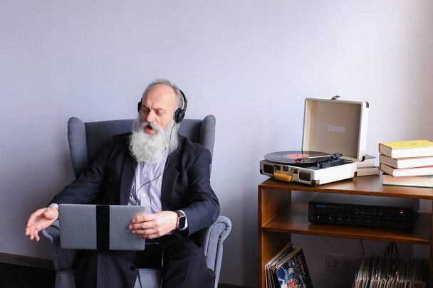 Male Elderly person enjoys listening to rock music on headphones - Foto, Bild