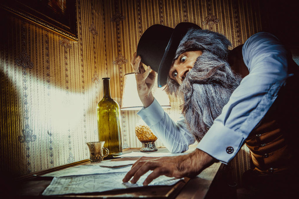 Bearded man reads a mysterious letter in the dark room - Photo, Image