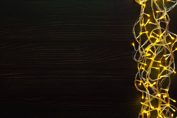 Christmas lights border on dark wooden background - Valokuva, kuva