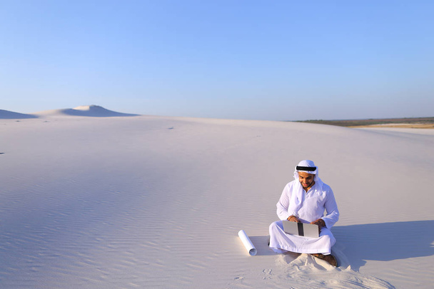 Architecte musulman assis avec ordinateur portable sur le sable dans le désert sur h
 - Photo, image