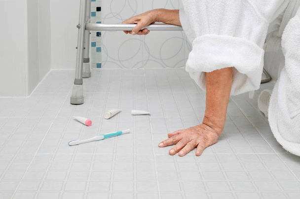 oudere vrouw vallen in de badkamer omdat gladde oppervlakken - Foto, afbeelding
