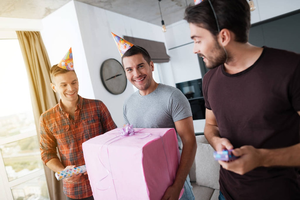 Men in birthday hats are showing to each other presents. - Photo, Image