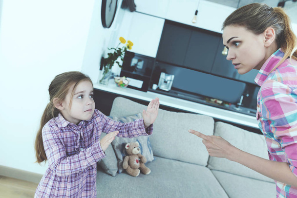 The little girl is frightened and protected from babysitting. She curses the girl and threatens her with a finger. - Photo, image