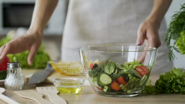 Woman adding salt in salad with vegetables in glass bowl, close-up video - Felvétel, videó