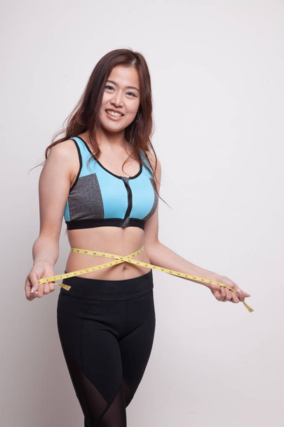 Beautiful Asian healthy girl measuring her waist. - Fotó, kép