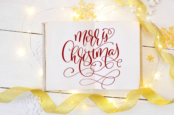 texto Feliz Navidad en un cuaderno de papel abierto, con cintas de oro y bolas de nieve. Fotografía para tarjeta de felicitación navideña, invitación, cartel del calendario
 - Foto, imagen