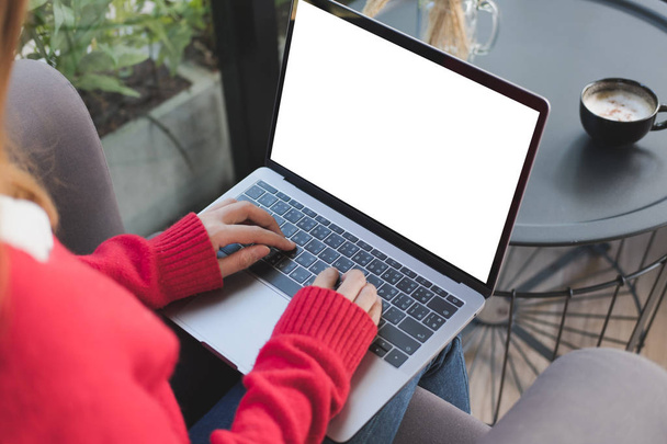 Egy piros pulóvert viselő nő gépel otthon a számítógépen. női adu - Fotó, kép