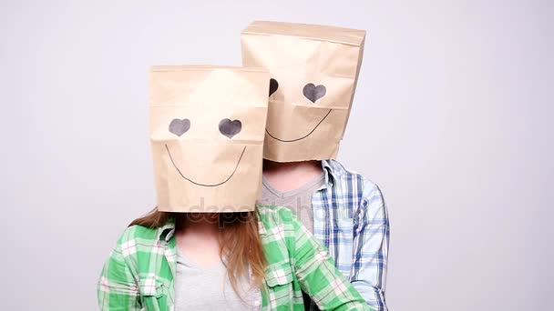 Jovem casal apaixonado por sacos sobre cabeças em fundo cinza
 - Filmagem, Vídeo