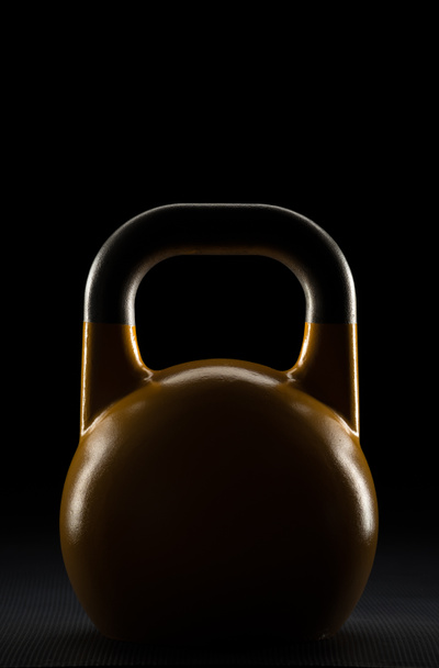 Rand gele competitie kettlebell silhouet aangestoken op een sportschool vloer - Foto, afbeelding