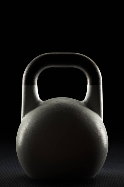 Backlit witte competitie kettlebell gewicht silhouet op een sportschool vloer - Foto, afbeelding