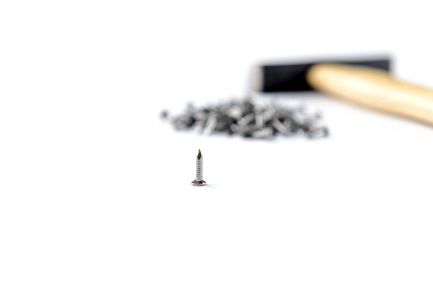 Scattering small iron nails  with hammer isolated on white background, close-up view - Photo, Image