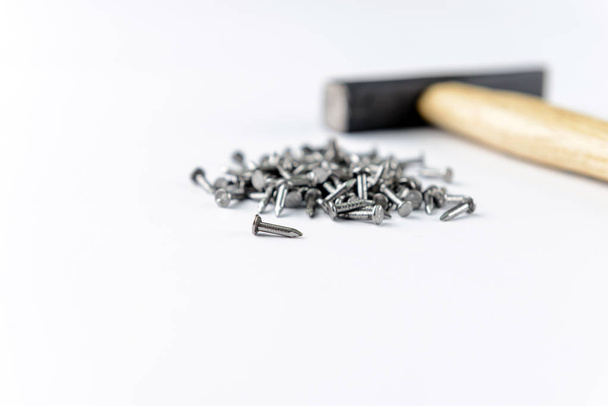 Espalhando pequenos pregos de ferro com martelo isolado no fundo branco, vista close-up
 - Foto, Imagem
