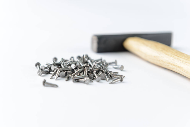 Scattering small iron nails  with hammer isolated on white background, close-up view - Photo, Image