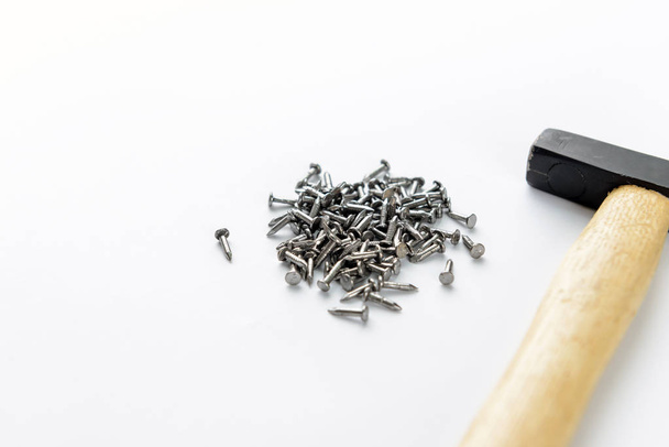 Verstrooiing van kleine ijzeren nagels met hamer geïsoleerd op een witte achtergrond, vergrote weergave - Foto, afbeelding