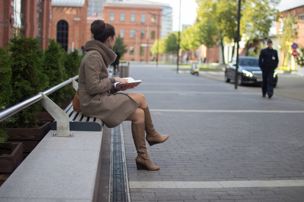 young woman sits on a bench - Фото, изображение