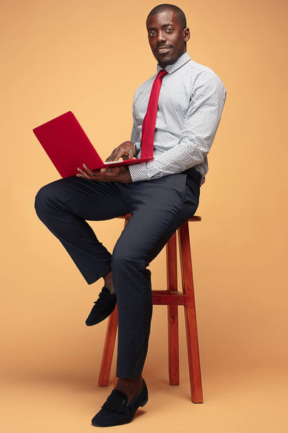 Handsome Afro American man sitting and using a laptop - Photo, image