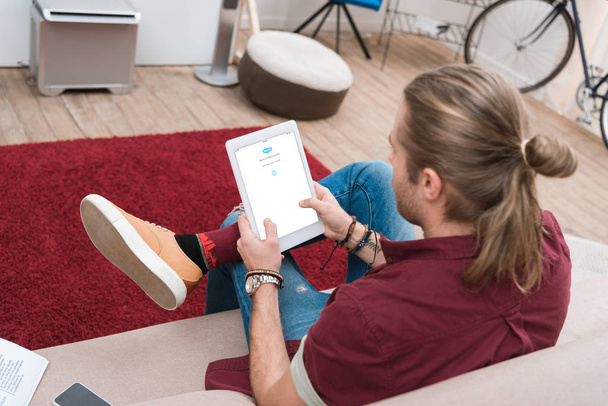 man sitting on sofa while using digital tablet with skype appliance - Zdjęcie, obraz