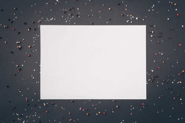 pohled shora bílý list papíru mezi rozptýlené pepř na šedý stůl - Fotografie, Obrázek