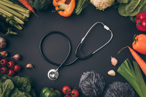 top view of stethoscope among vegetables on gray table - Photo, Image