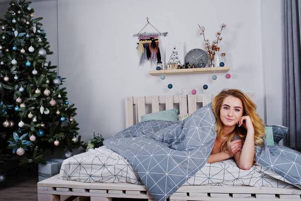 Sexy naked blonde model on bed with christmas gift boxes against - Photo, Image