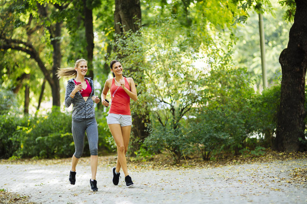 Two sporty women jogging in city - Photo, image