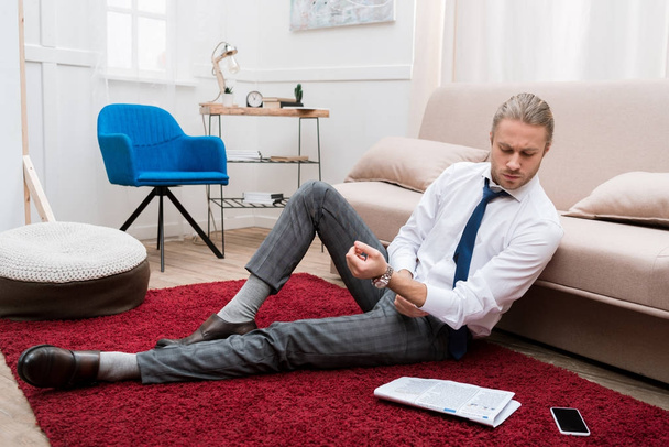 Üzletember, a szőnyegen, a nappaliban ült és olvasó újság  - Fotó, kép