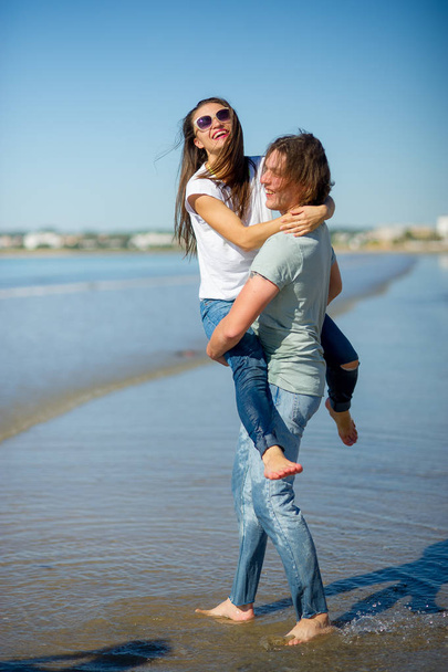 On the seashore the guy holds the girl on hands. - 写真・画像
