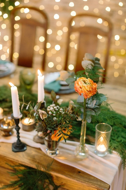 wedding decor, romance, love concept. on the blured background with numerous of twinkle lights there are posies made of roses and various leaves and tall and small candles - Valokuva, kuva