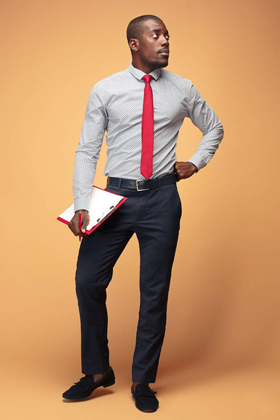 Atractivo hombre de negocios afroamericano de pie escribiendo notas
 - Foto, imagen