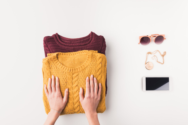 руки со свитерами, аксессуарами и смартфоном
 - Фото, изображение