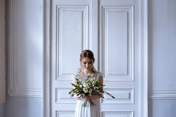 Beauty bride in bridal gown with bouquet indoors - Фото, изображение