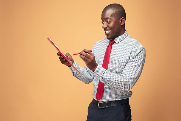 Attractive standing Afro-American businessman writing notes - 写真・画像