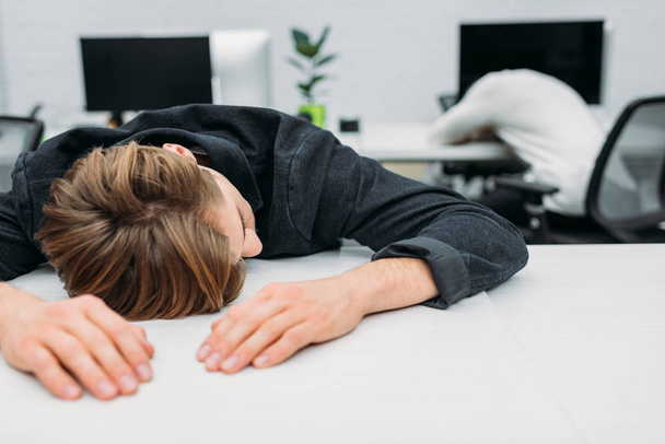 przepracowany młody Menedżer spanie na pracę w nowoczesnym biurze - Zdjęcie, obraz