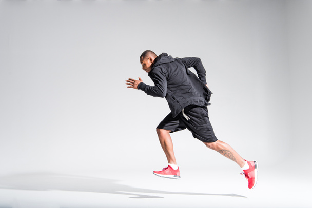 vista lateral del joven deportista afroamericano corriendo sobre gris
 - Foto, Imagen