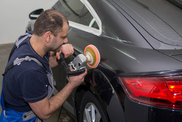 A man polishes a black car - Фото, изображение
