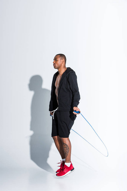 young african american sportsman exercising with skipping rope on grey - Photo, Image