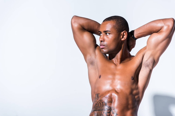 muscular shirtless african american sportsman with hands behind head looking away isolated on grey  - Foto, Imagen
