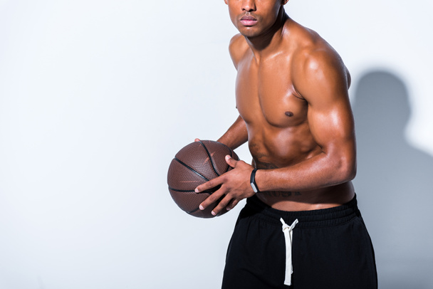 cropped shot of shirtless african american man holding basketball ball on grey  - Fotografie, Obrázek