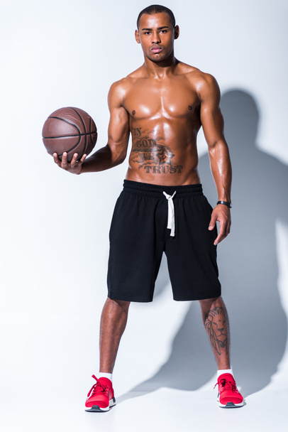 teljes hossza nézet sportos félmeztelen afrikai amerikai férfi kosárlabda labda látszó-nél fényképezőgép szürke  - Fotó, kép