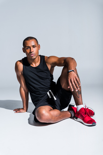 young african american sportsman wearing fitness tracker and looking at camera on grey - Foto, Imagen