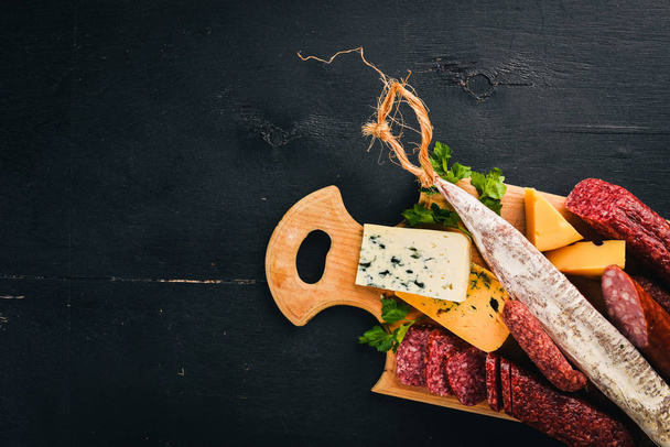 Assortment of cheeses and traditional sausages on a wooden background. Brie cheese, blue cheese, gorgonzola, fuete, salami. Free space for text. Top view. - Фото, зображення