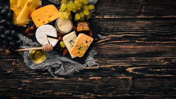 Grapes, red wine, cheeses, honey and nuts on a wooden background. Top view. - Фото, зображення