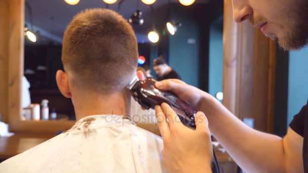 Uomo barbiere taglio capelli di cliente maschile con clipper al negozio di barbiere. Processo di acconciatura. Rallentatore Close up
 - Filmati, video