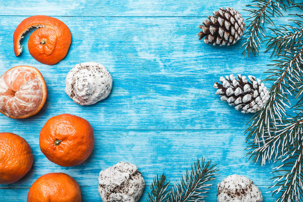 Wallpaper of azure wood, open, sea. Mandarins. Green fir tree. Decorative cones. Space for Xmas and New Year Message. Sweets for holidays. Xmas and Happy New Year composition. - Foto, imagen